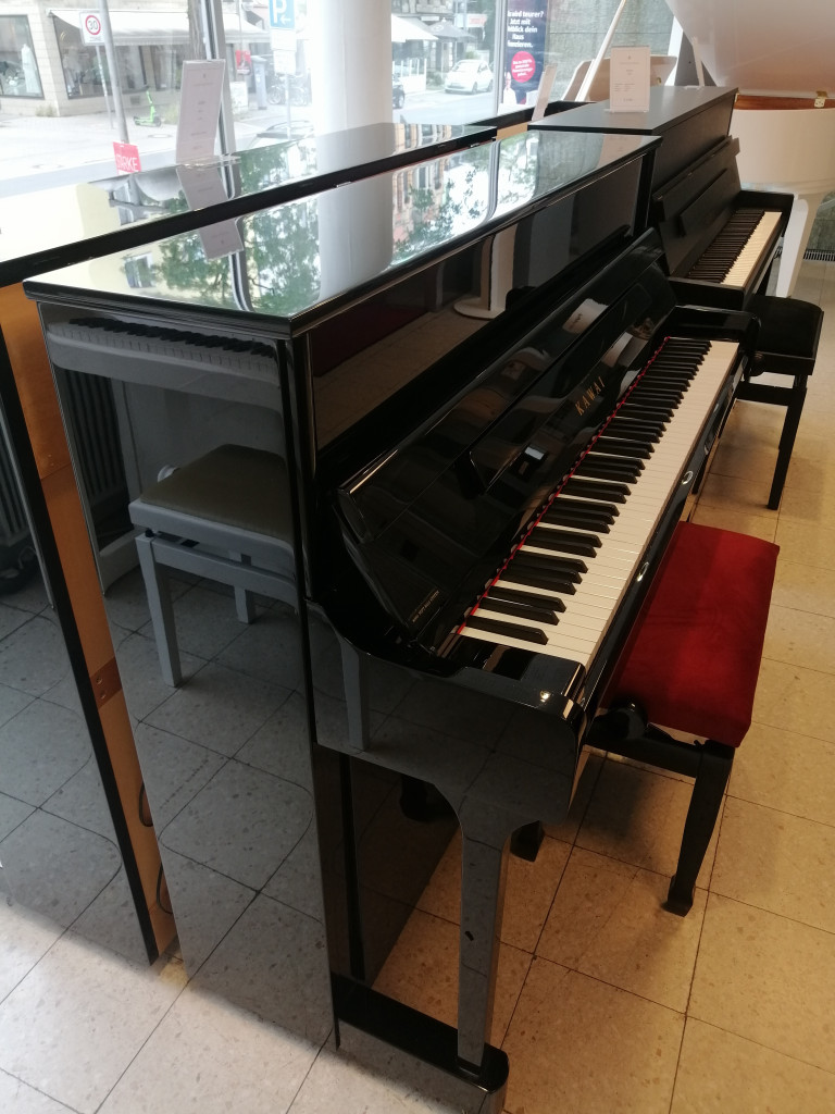 Schwarzes Kawai Klavier mit roter Klavierbank in einem Musikgeschäft