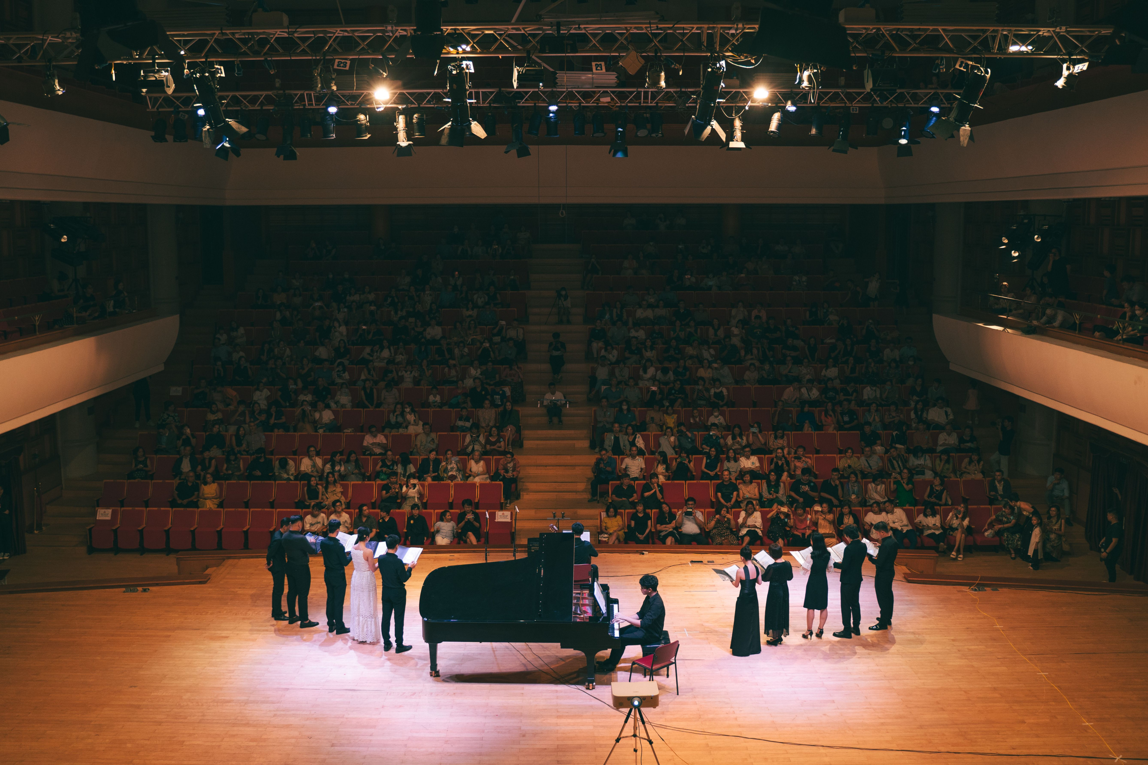 Konzertsaal mit Klavier und Musikern auf der Bühne vor großem Publikum
