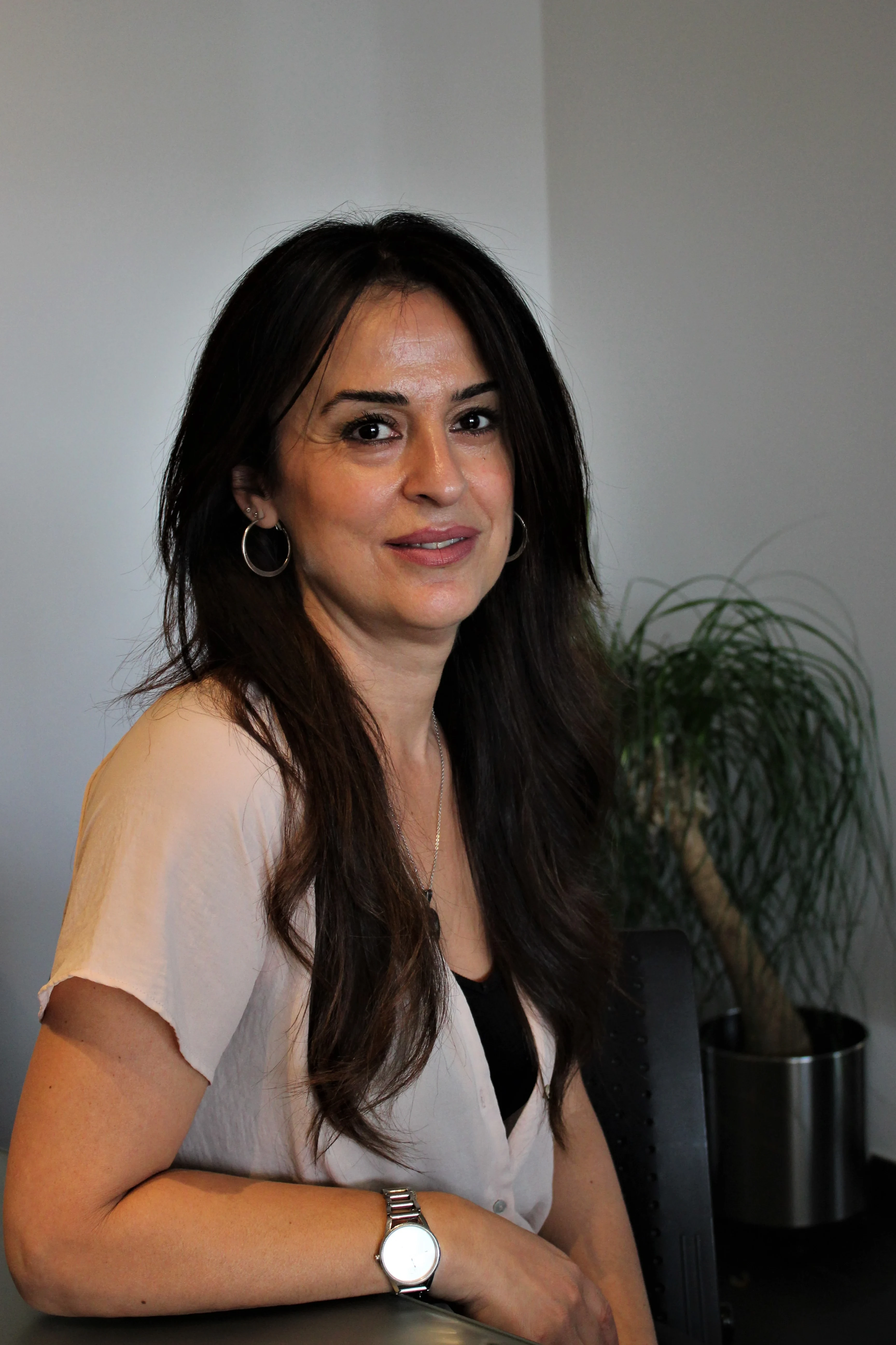 Aynur Vural sitzt in einem modernen Büro mit Pflanze im Hintergrund