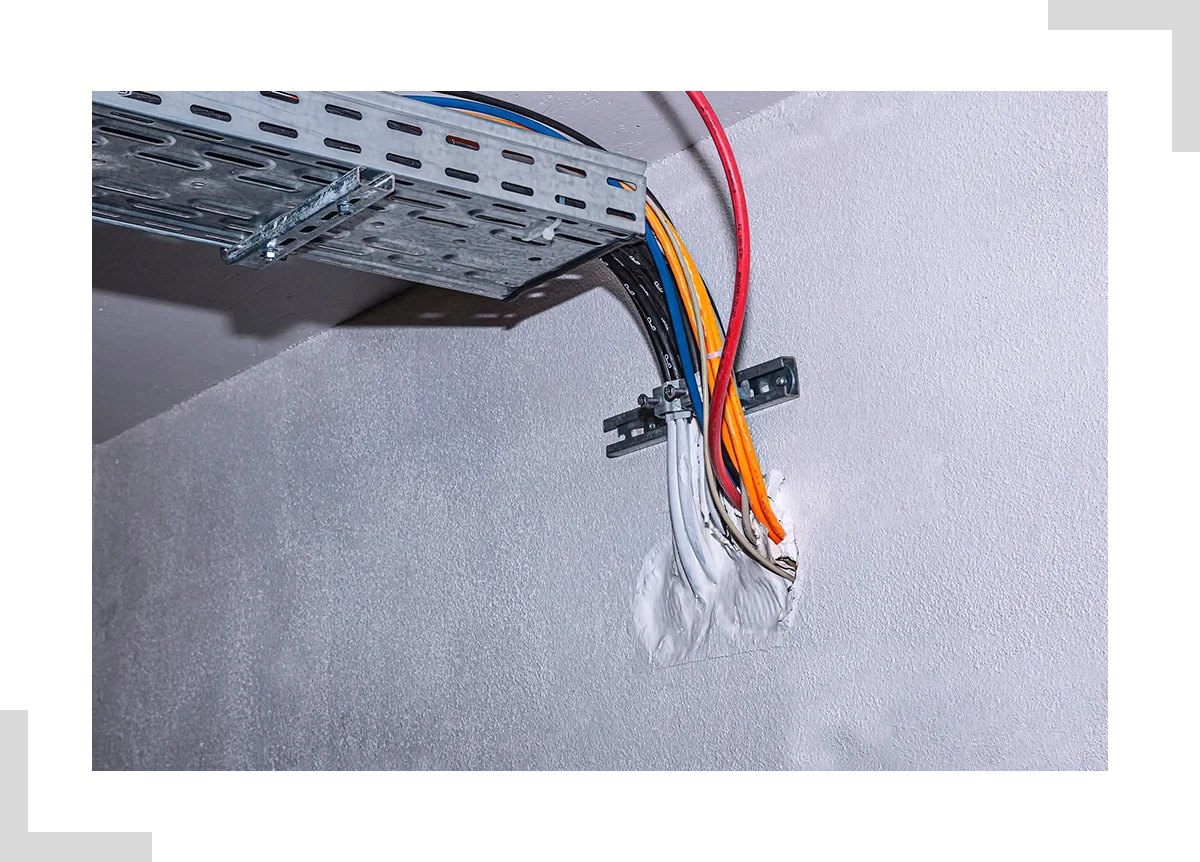 Brandschutz an Kabeldurchführung in einer Wand – verschiedene Kabel und Kabeltrasse mit Brandschutzabdichtung