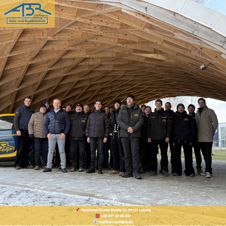 Gruppenfoto des Teams von ABR Holz- und Bautenschutz vor moderner Holzkonstruktion in Leipzig