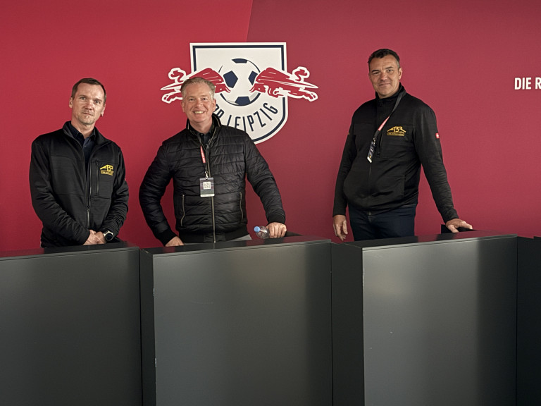 Drei Personen vor RB Leipzig Logo in einem modernen Raum
