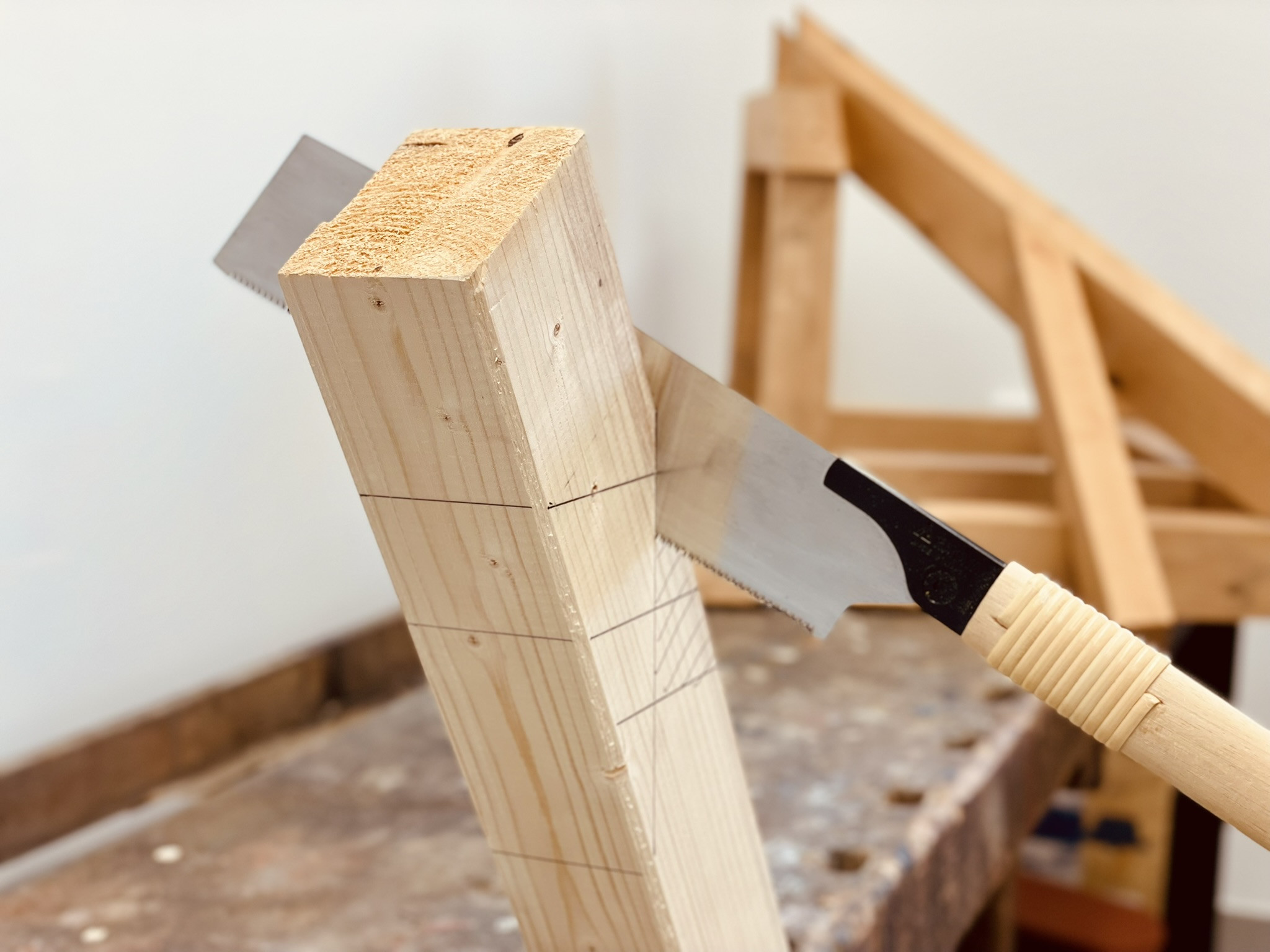 Holzbalken wird mit einer japanischen Säge in einer Werkstatt zugesägt