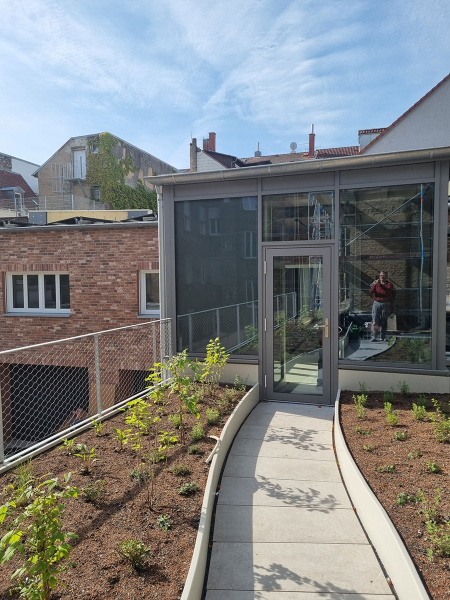 Modernes Fenster auf einer Dachterrasse mit Begrünung und Glasfront in urbaner Umgebung