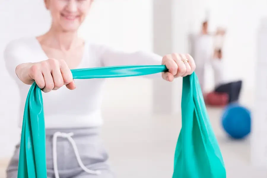 Frau macht Physiotherapie-Übung mit Theraband, freundliche Atmosphäre, Startseite