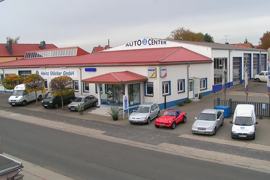 Außenansicht des Auto Center Heinz Stöcker GmbH mit geparkten Autos vor dem Gebäude