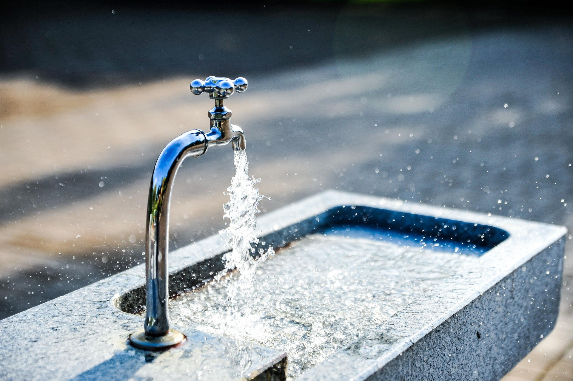 Wasserhahn mit fließendem Wasser an einem Brunnen im Freien