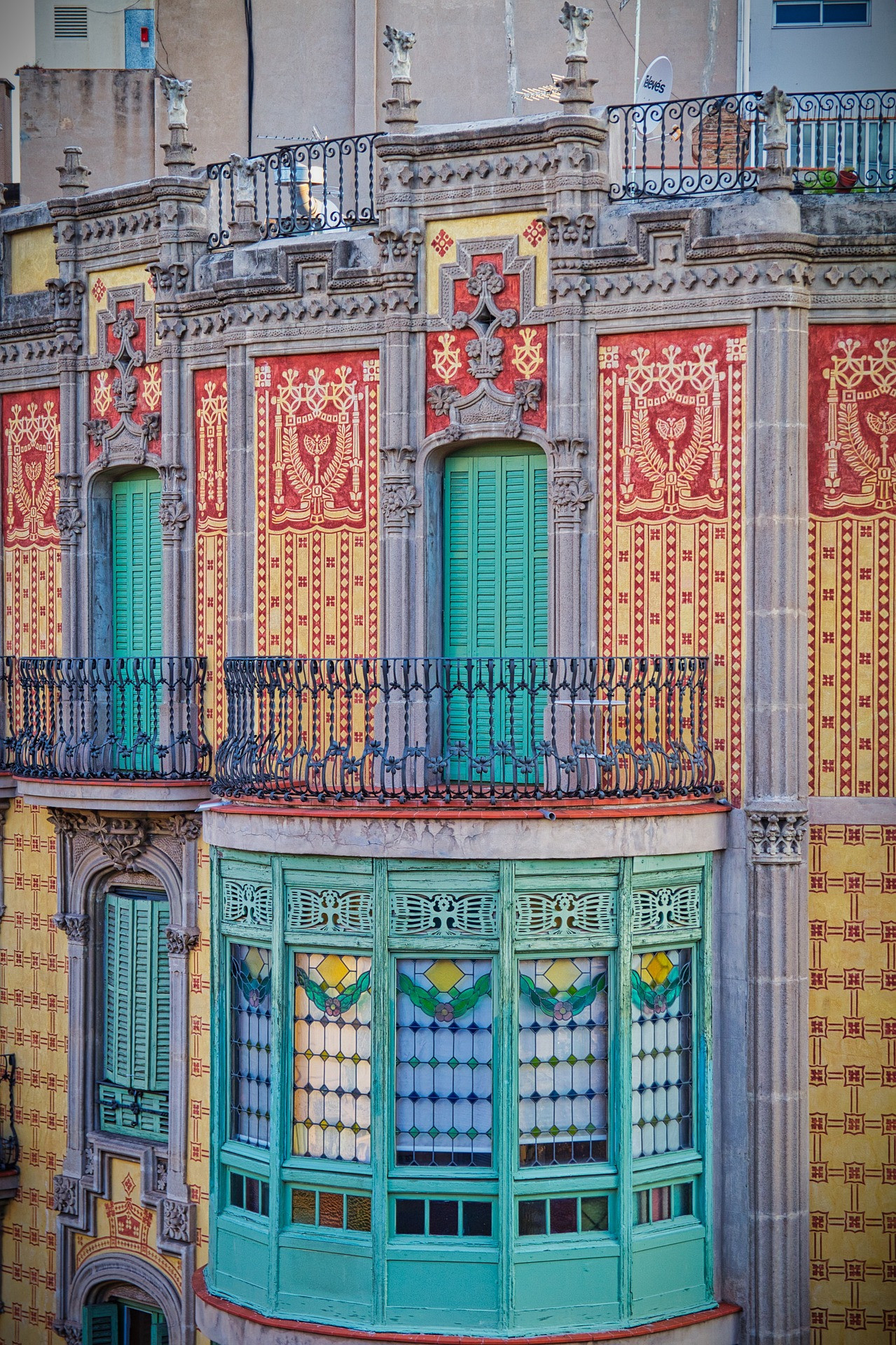 Bunte Wand mit kunstvollen Verzierungen und grünen Fensterläden an einem historischen Gebäude