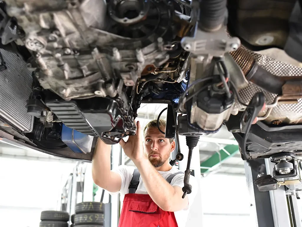 Automechaniker repariert defektes Fahrzeug auf der Hebebühne in einer Werkstatt