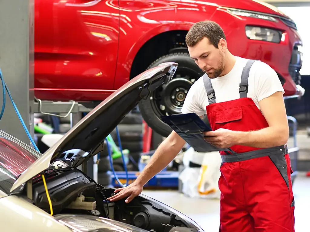 Kundendienst in einer Autowerkstatt: Mechaniker kontrolliert Fahrzeug