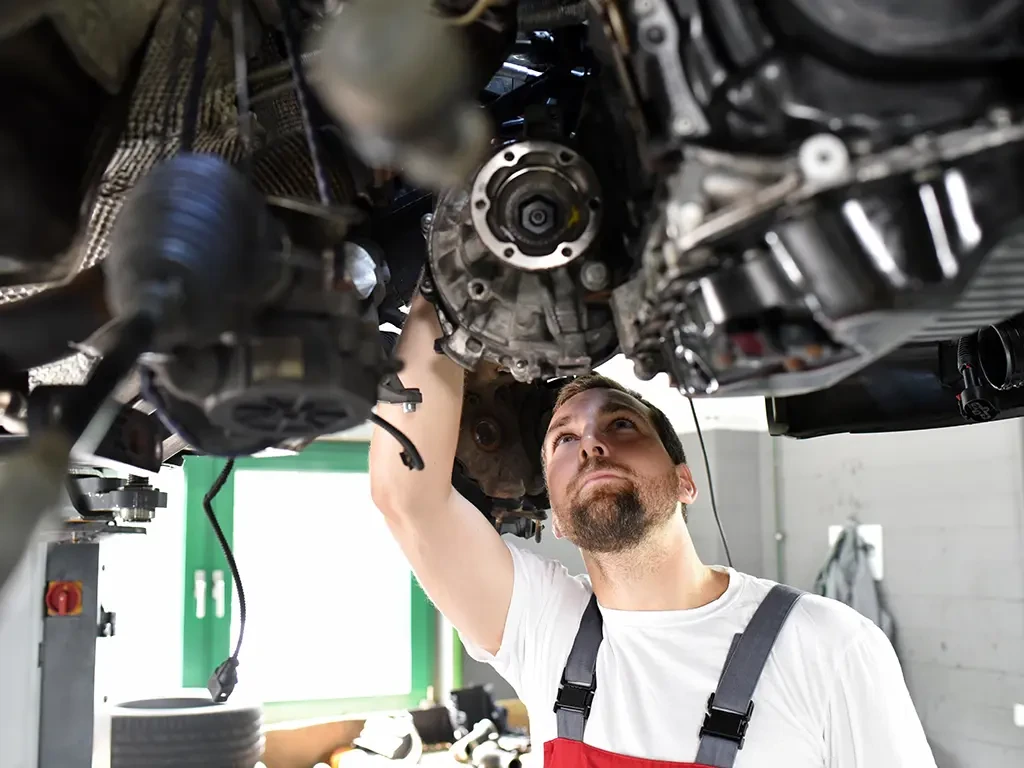 Automechaniker in Arbeitskleidung prüft den Motor eines Autos in einer Werkstatt