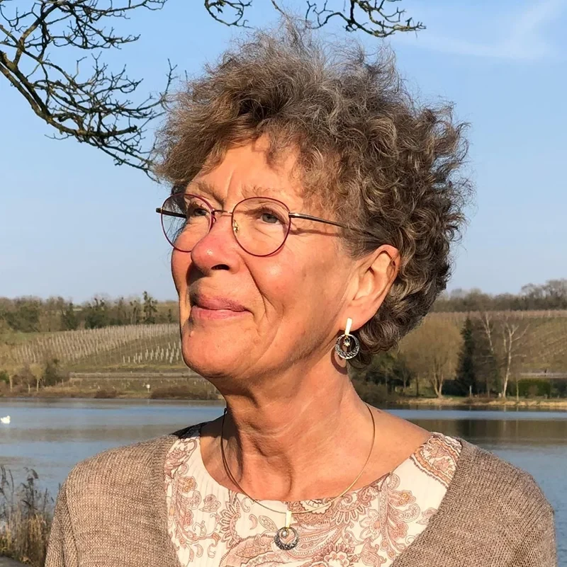 Portrait von Viviane Hauger-Schmit vor einer natürlichen Landschaft mit See und Feldern