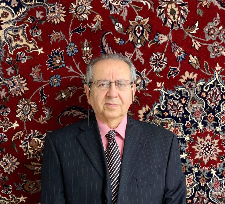 Mann im Anzug vor orientalischem Teppich mit floralen Mustern