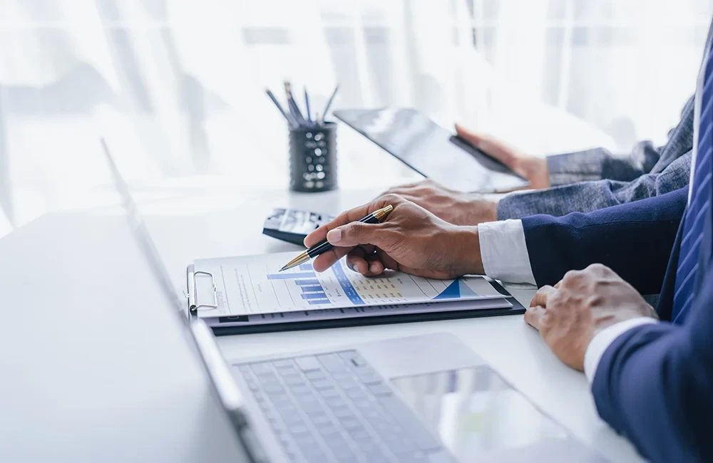 Zwei Personen analysieren Buchhaltungsunterlagen und Diagramme im Büro