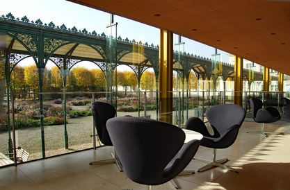 Modernes Café mit Blick auf einen historischen Garten durch große Glasfenster