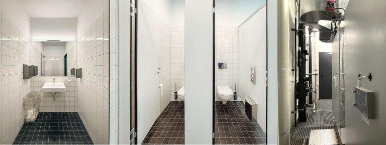 Sanierung Conti-Hochhaus Ensemble – Moderne Toilettenräume nach Renovierung am 01.10.2026 Sanierung Conti-Hochhaus Ensemble: Moderne WC-Anlagen mit weißen Fliesen und dunklem Boden, fotografiert am 01.10.2026