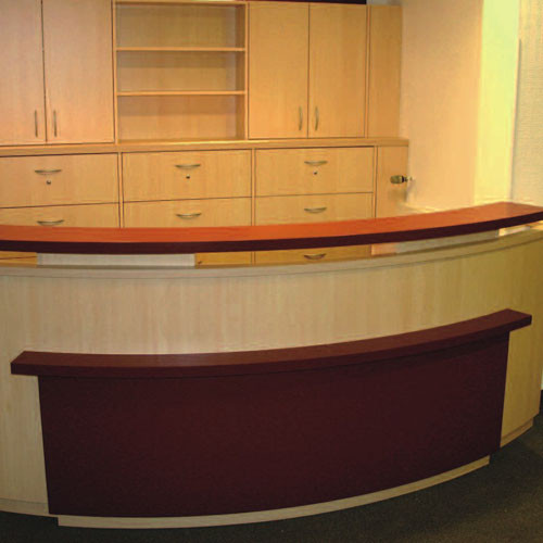 Moderner Empfangstresen in einer Arztpraxis mit Holzverkleidung und Regalen im Hintergrund