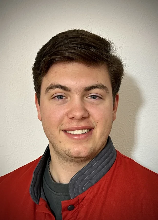 Robin Schomaker als Auszubildender in Arbeitskleidung vor heller Wand