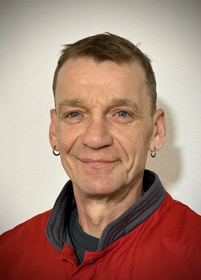 Portrait von Mario Paech mit roter Jacke vor hellem Hintergrund