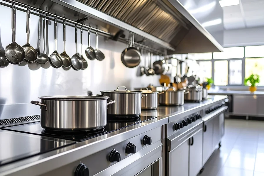 Hochwertiges Geschirr und Töpfe aus Edelstahl in einer professionellen Küche Professionelles Küchen-Geschirr aus Edelstahl in einer modernen Großküche