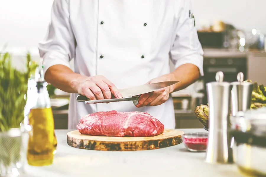 Fleischer beim Schärfen des Messers und Vorbereiten von Fleisch in der Metzgerei Fleischer schärft Messer und bereitet frisches Fleisch in der Metzgerei vor