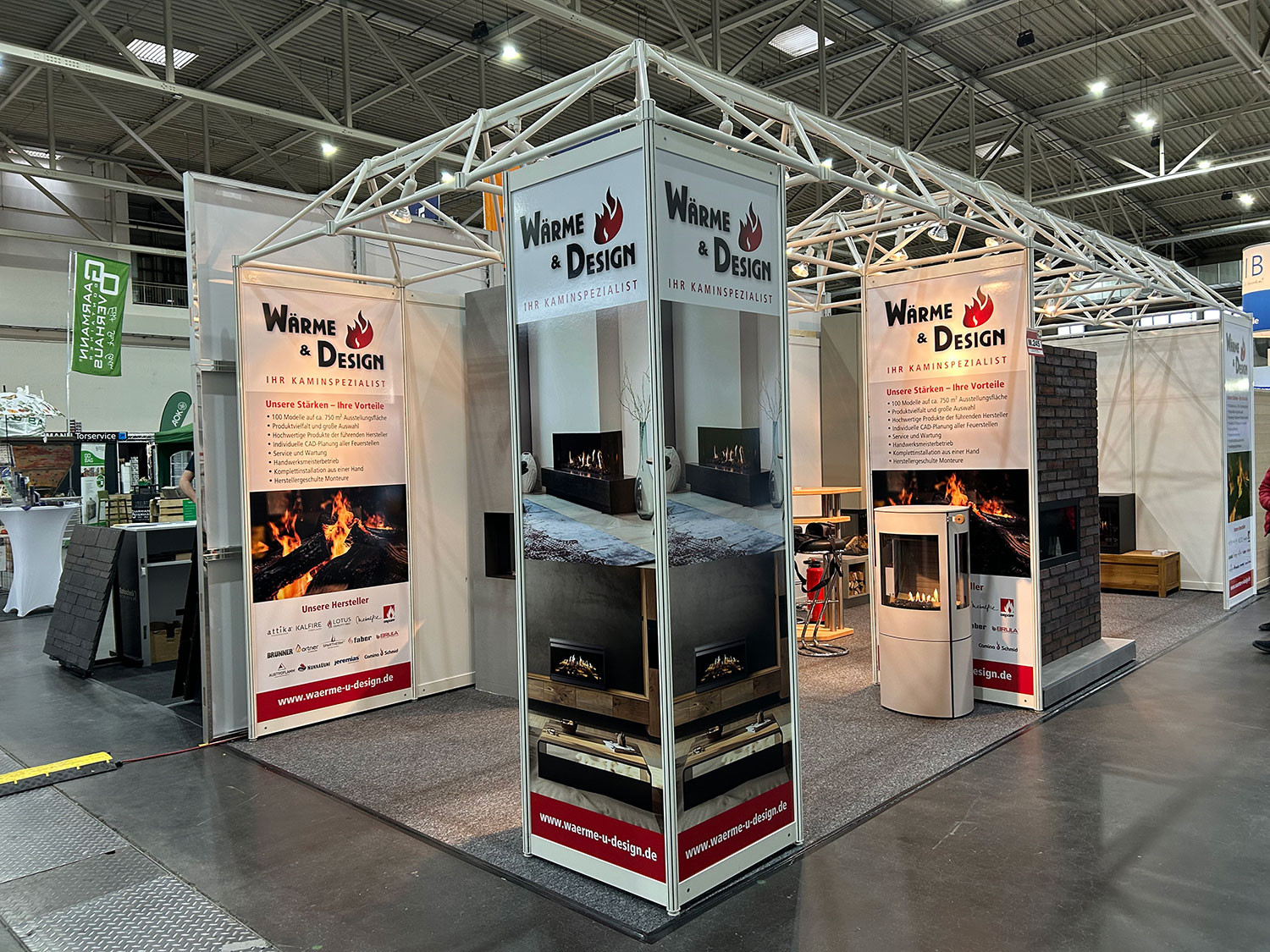 Messestand von WÄRME & DESIGN auf einer Messe, Kaminöfen und Informationsbanner zum Kaminspezialisten