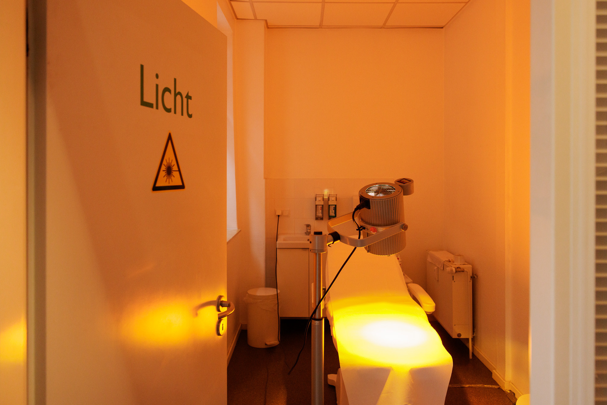 Praxisfoto: Behandlungsraum mit Lichttherapie-Gerät und Liege Praxisfoto eines Behandlungsraums mit Lichttherapie-Gerät und Liege