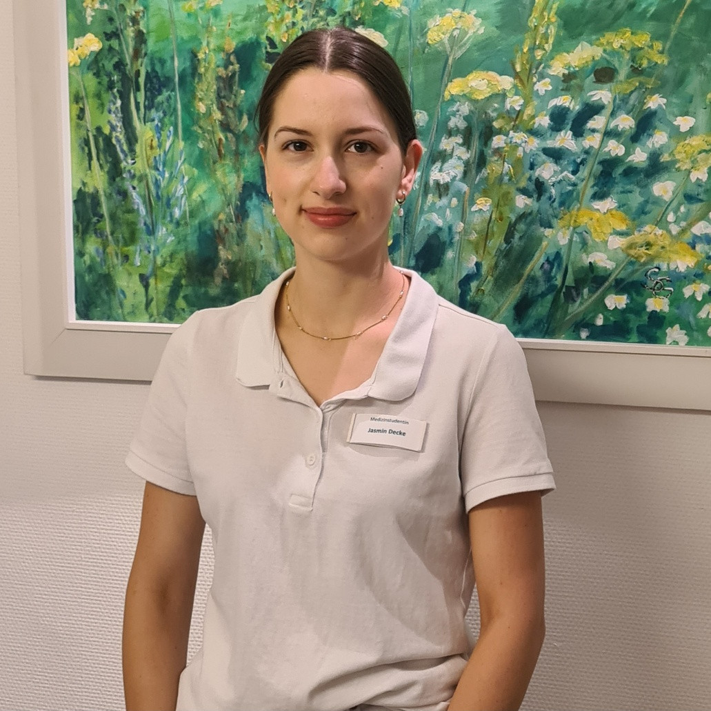 Jasmin in weißem Polohemd vor Blumenbild Jasmin in weißem Polohemd vor einem Gemälde mit Blumenmotiv