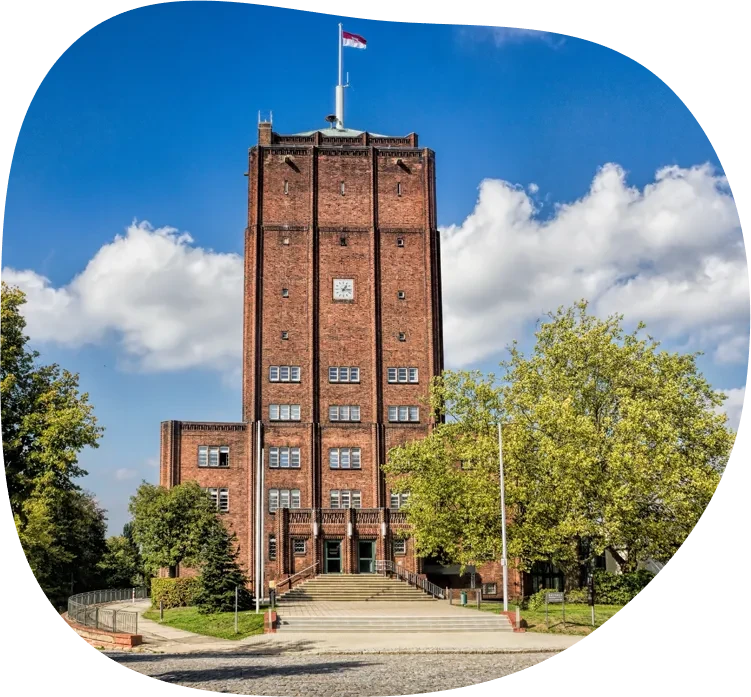 Rathaus Neuenhagen bei Berlin vor blauem Himmel mit Bäumen im Vordergrund