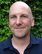 Porträt von Daniel Balschun vor grünem Hintergrund