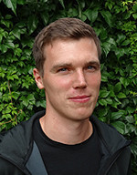 Portrait von Stefan Krug vor einer grünen Hecke
