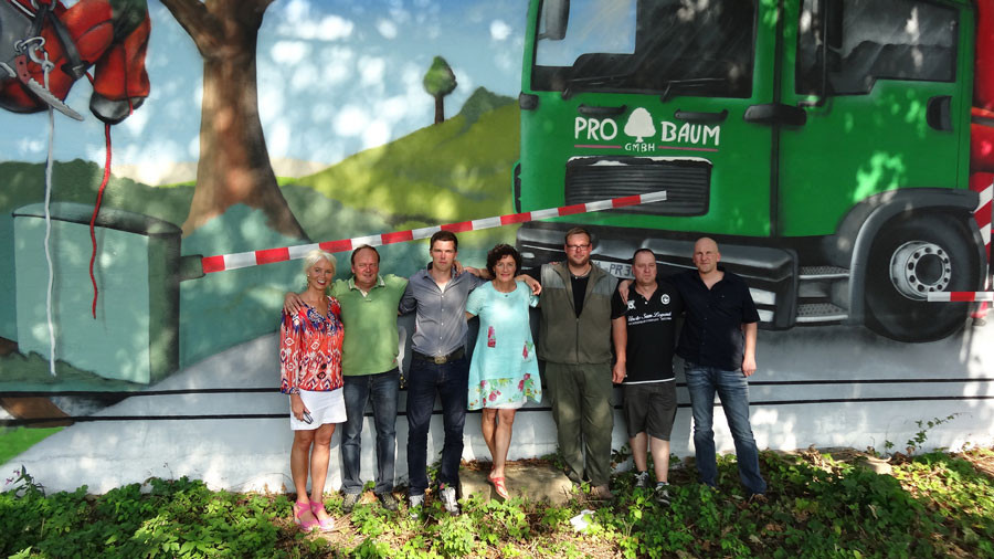 Teamfoto vor bemalter Wand mit Pro Baum GmbH LKW-Motiv
