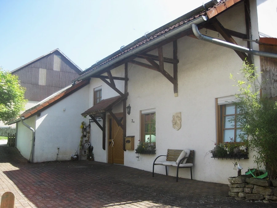 Vorderansicht eines Hauses mit Bank und Blumen Vorderansicht eines Hauses mit Bank und Blumen