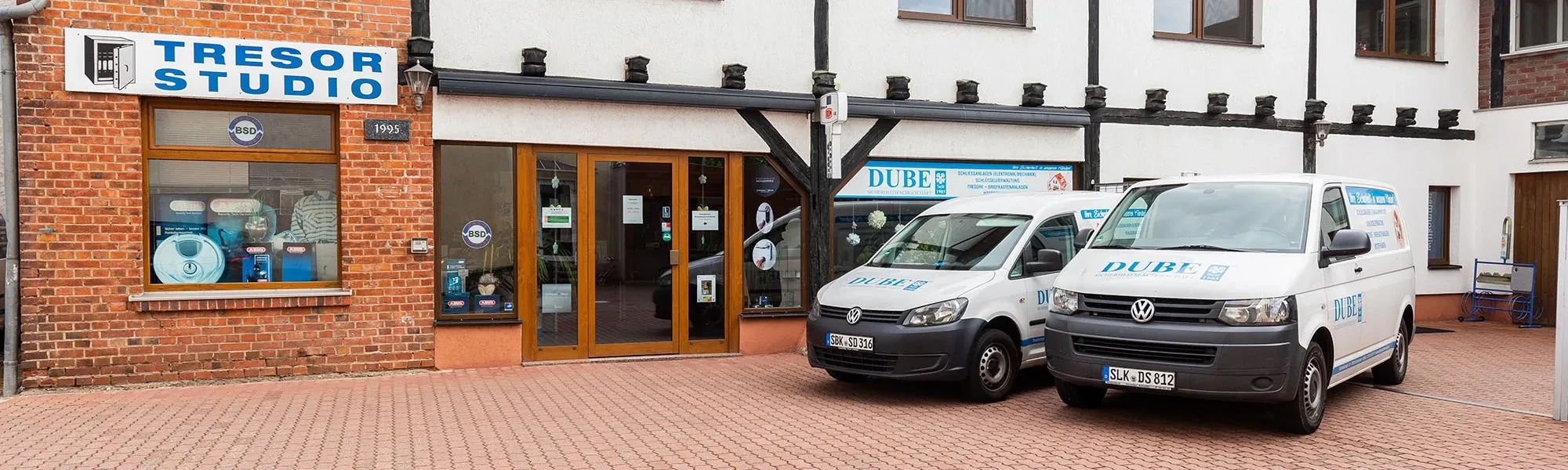 Ladengeschäft mit DUBE Sicherheitsnachschlüssel-Service und Firmenfahrzeug vor dem Eingang
