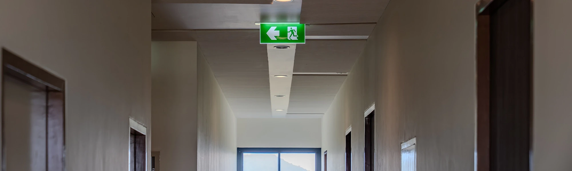 Fluchttüren Notausgang Schild in einem Flur mit grünem Rettungszeichen