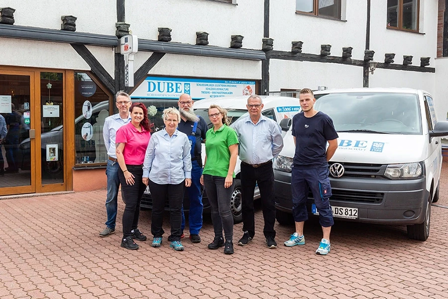 Teamfoto der Firma DUBE Schlüsseldienst vor dem Firmengebäude und Firmenfahrzeugen