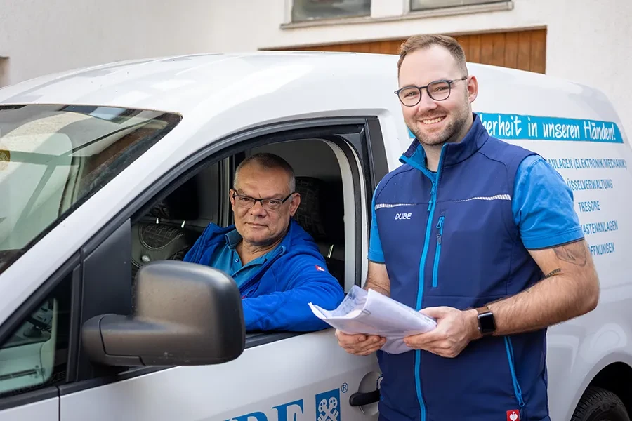 Zwei freundliche Handwerker starten ihren Arbeitstag am Firmenfahrzeug