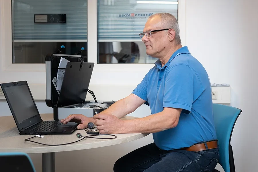 Fachmann arbeitet an Schließanlagen, moderner Arbeitsplatz mit Laptop und Schlüsseln