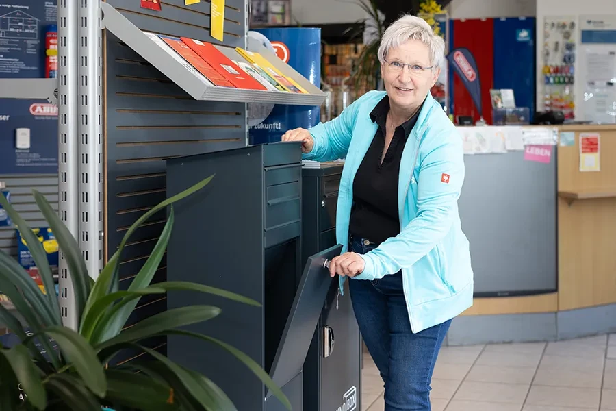 Frau benutzt einen CON-TEN Tresore Paketbriefkasten in einem Geschäft