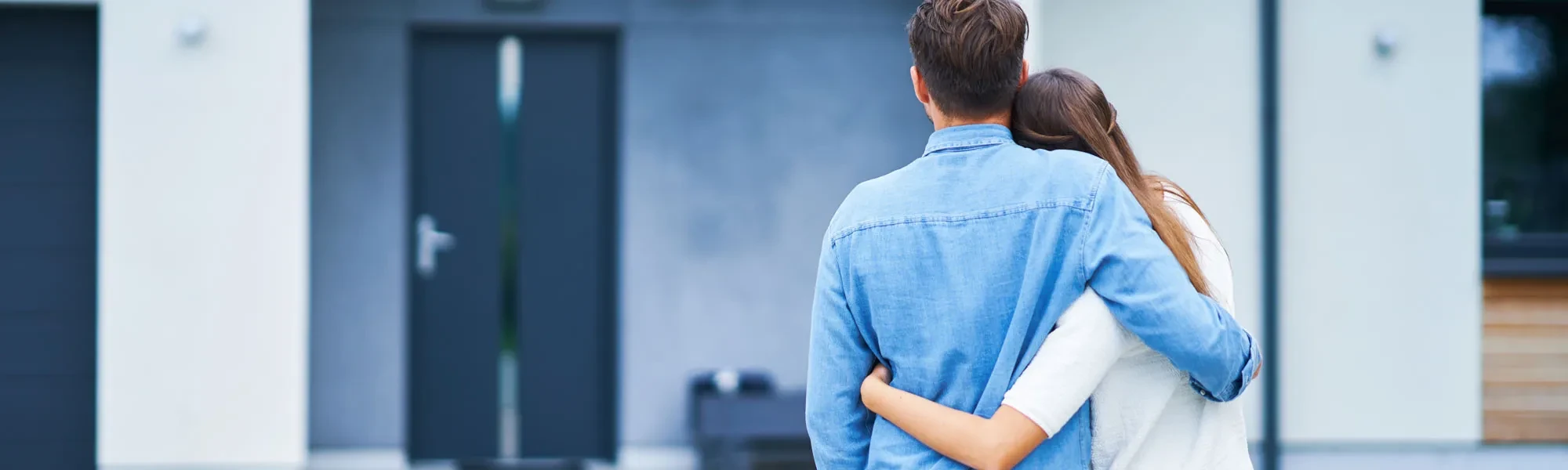 Header privat neu: Paar von hinten, Mann in Jeanshemd, Arm um die Schulter, modernes Ambiente