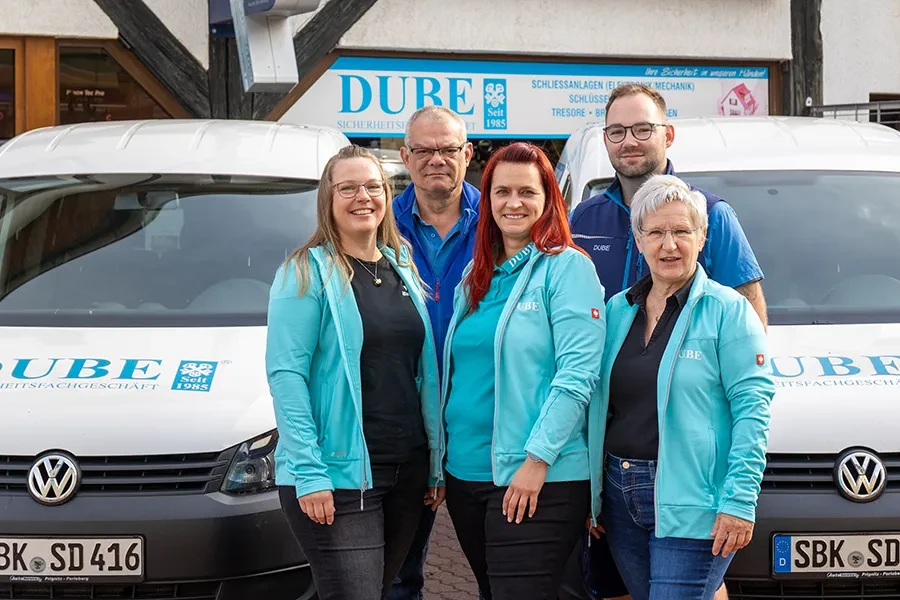 Teamfoto eines Familienunternehmens vor Firmenfahrzeugen und DUBE Sicherheitsdienst Schild