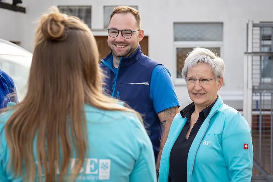 Teamfoto für die Über-uns-Seite – freundliche Mitarbeiter im Gespräch vor dem Firmengebäude