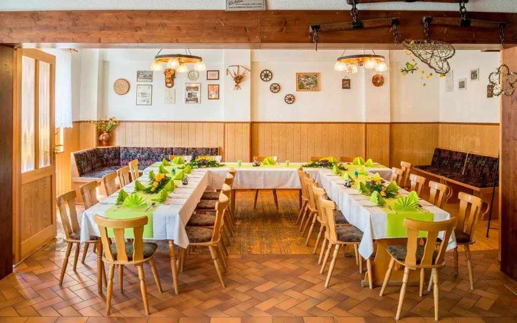 Gastraum mit festlich gedeckten Tischen, Holzstühlen und dekorativer Wandgestaltung