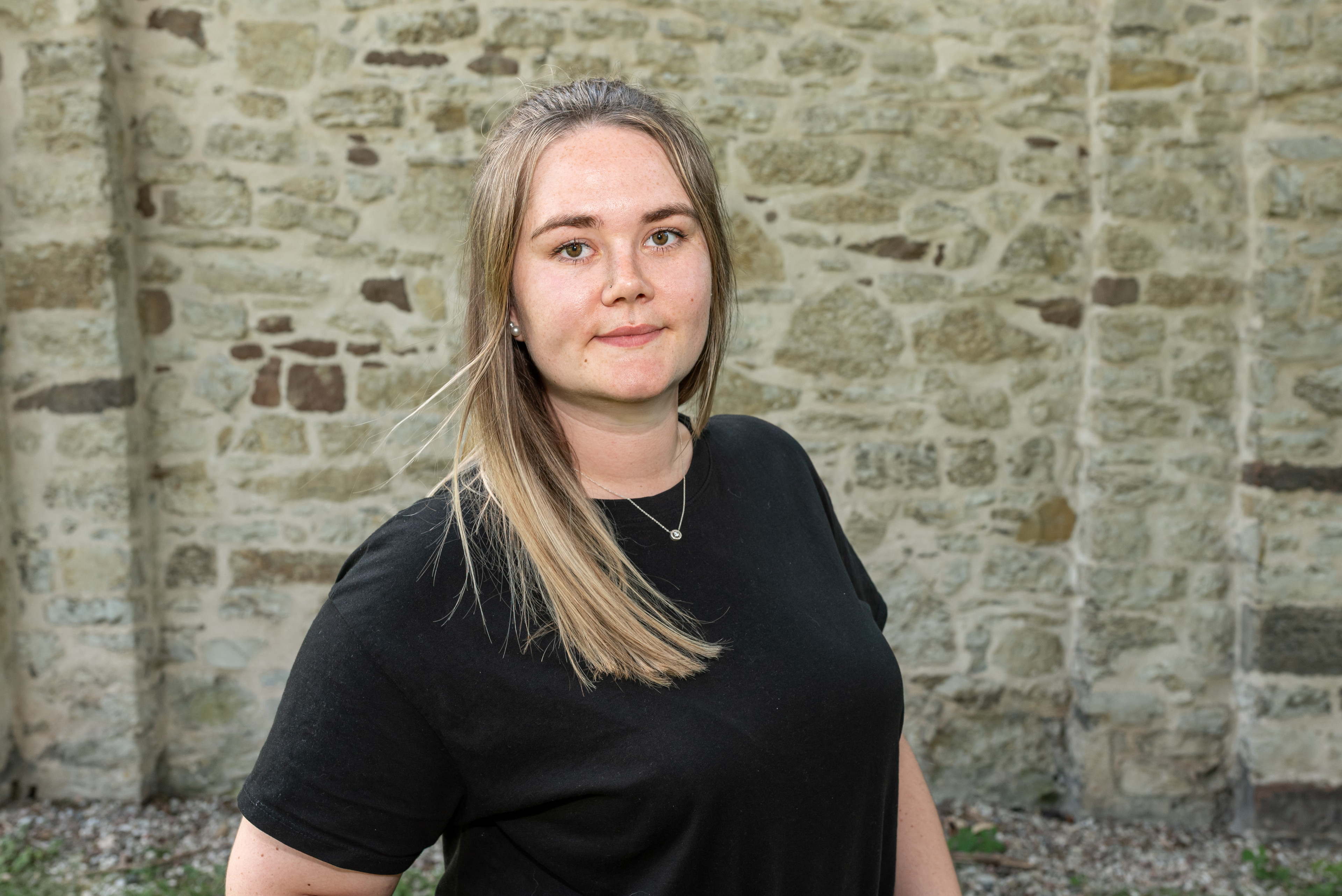 Anna vor einer alten Steinmauer im Freien