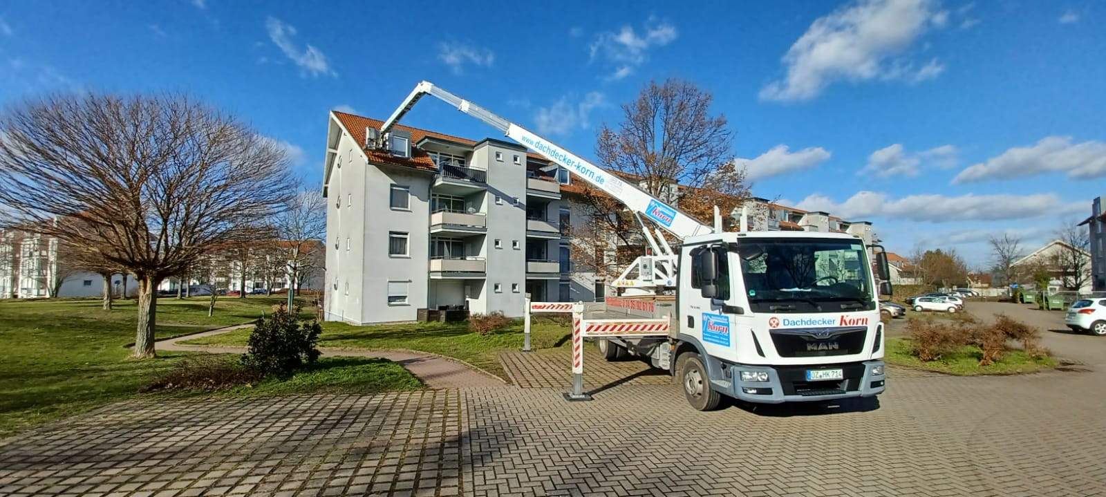 Dachdecker Korn bei Dacharbeiten an einem Mehrfamilienhaus mit Hubsteiger