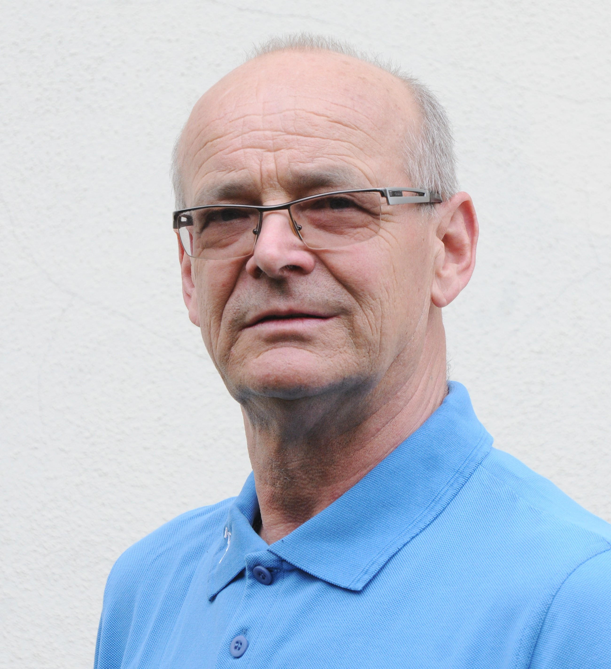 Ralf Korn im blauen Hemd vor hellem Hintergrund