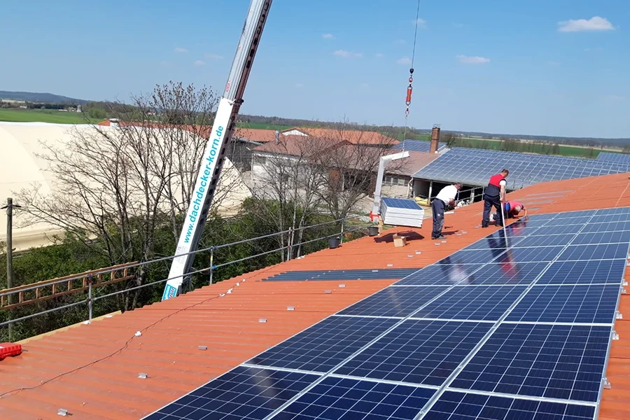 Installation von PV-Modulen auf einem Dach mit Kran und Handwerkern