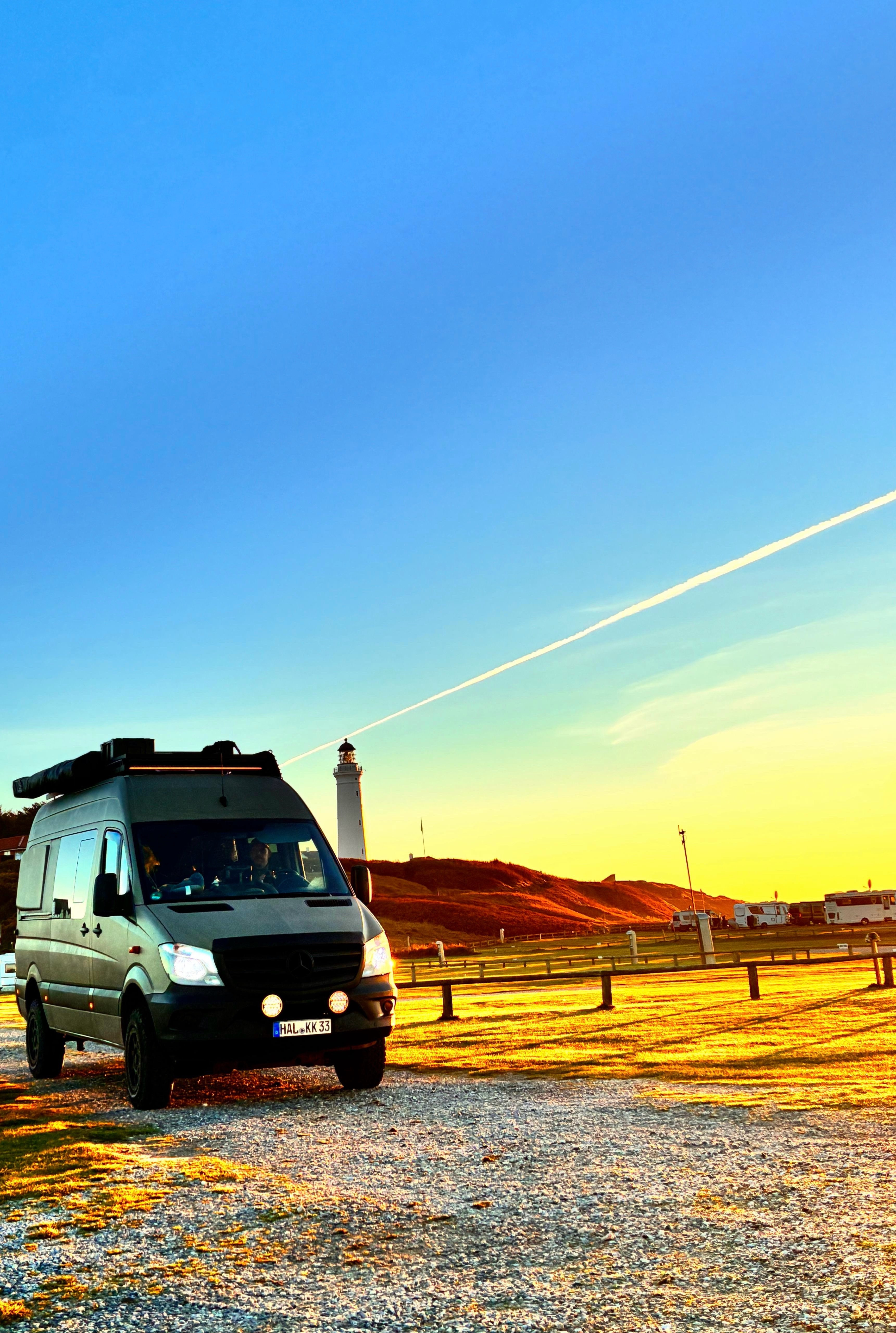 Freiheit auf Rädern: Das mobile Eigenheim – Campervan vor Leuchtturm bei Sonnenuntergang