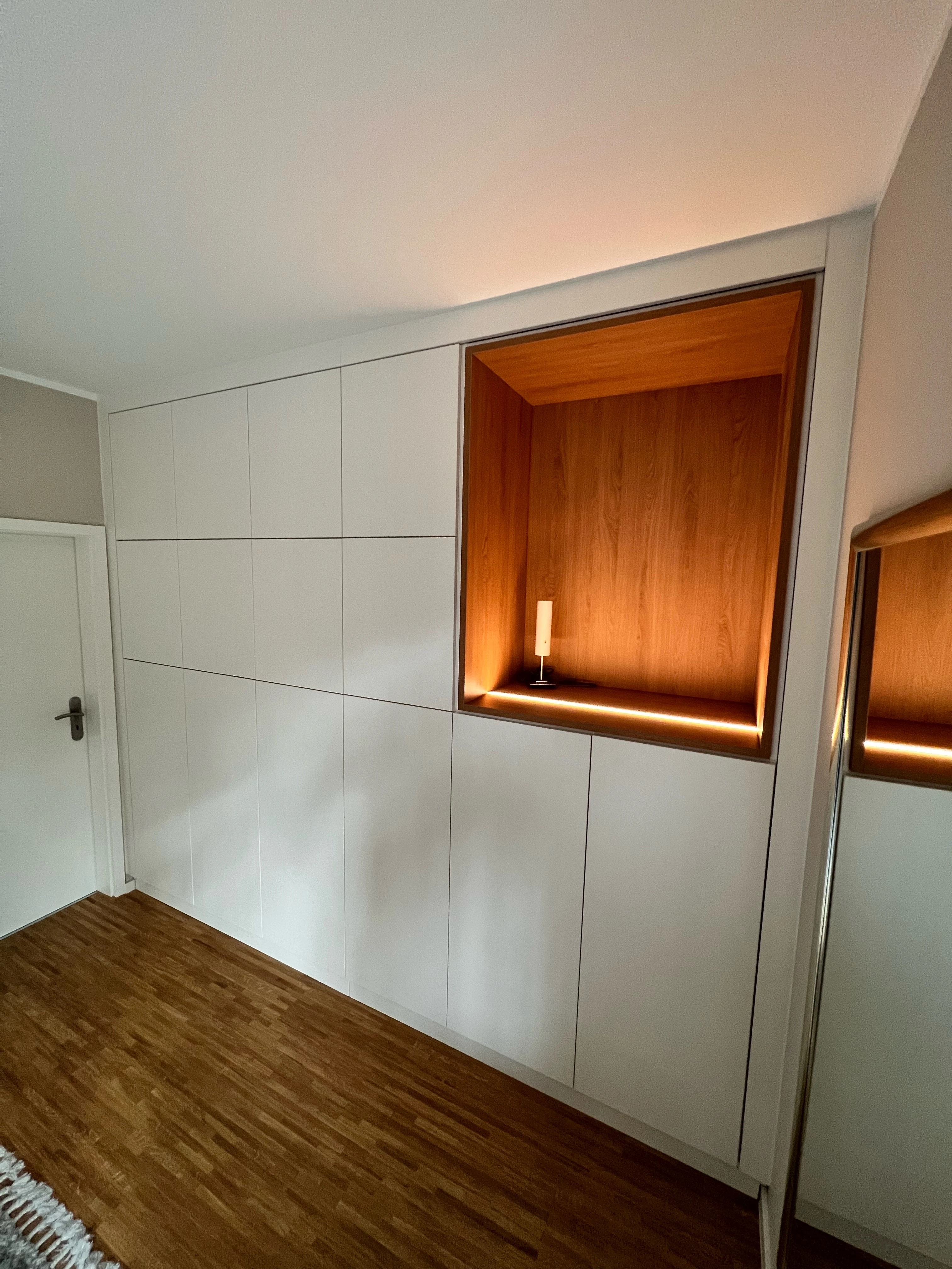 Moderne Einbauschrankwand mit Holz-Nische und indirekter Beleuchtung, aufgenommen am 16. Dezember 2025