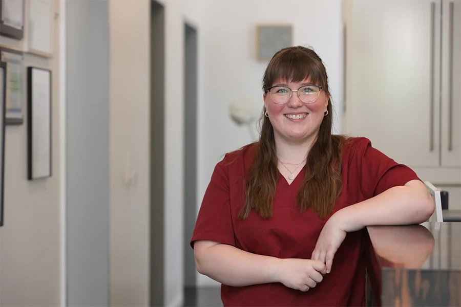 Julia Lange in roter Arbeitskleidung in einer Praxis